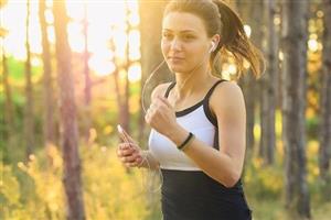 Female runner in the woods with music